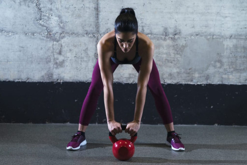 Fitness woman in sports clothes exercising with kettle bell weig